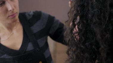 Kıvırcık saçlı akşam makyaj ile modeli için makyaj sanatçısı yapar. Güzel kadın kız üzerinde uygulanan kozmetik cilt yüz. Ağır çekim. Bayanlar güzellik salonda portresi kapatın.