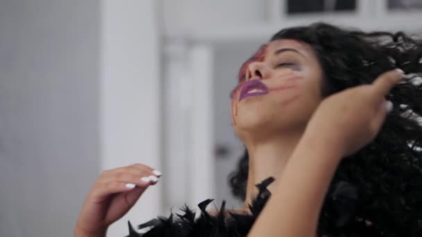 Retrato assustador de menina com maquiagem de sangue de Halloween. Mulher latina bonita coloca o cabelo encaracolado para baixo perto do espelho no camarim. Movimento lento . — Vídeo de Stock