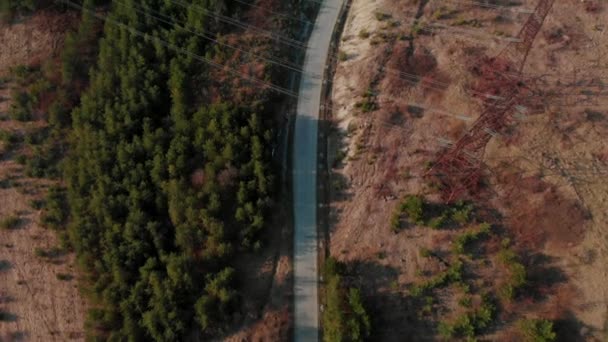 Εναέρια άποψη επαρχιακής οδού. Κινηματογραφική τονισμένο. βολή drone πετάει πάνω από ηλεκτρικά καλώδια και ασφαλτοστρωμένος δρόμος. Όμορφη φθινοπωρινή σεζόν — Αρχείο Βίντεο