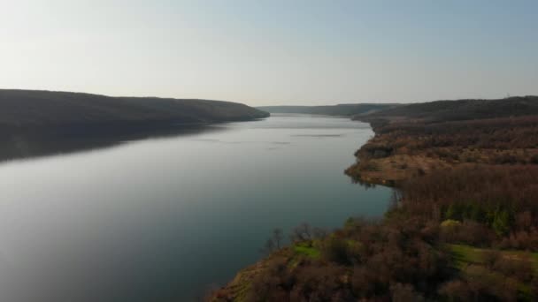 Vista aérea do drone. Voando sobre o belo lago ou rio perto de montanhas. Panorama de paisagem incrível. Cinemático tonificado. Dia lindo ensolarado — Vídeo de Stock