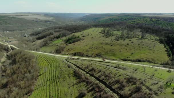 Drone πετάει πάνω από καταπράσινους λόφους και δρόμος με γρήγορη οδήγηση το αυτοκίνητο. Εναέρια άποψη επαρχιακής οδού. Κινηματογραφική τονισμένο. Πεδίο φυτεία ρυζιού βεράντα. Beautful τοπίο — Αρχείο Βίντεο