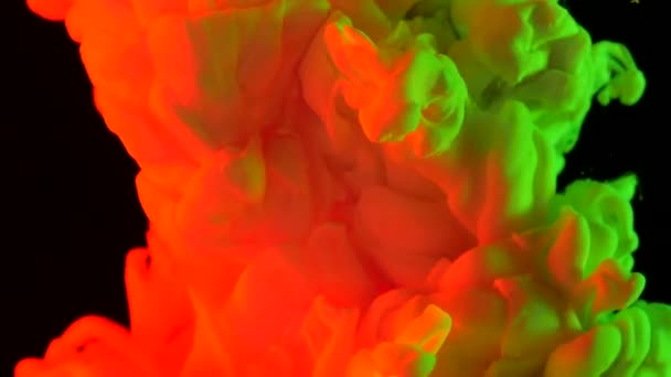 Orangefarbene und saure grüne Tinte bei Wasseraufnahmen mit Hochgeschwindigkeitskameras. Mischfarben fielen, reagierten, schufen abstrakte Wolkenformationen und Metamorphosen auf Schwarz. Kunstgeschichte. — Stockvideo