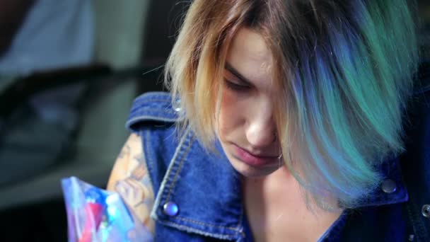 젊은 아름 다운 금발의 여 자가 초상화. 집중된 아티스트 소녀는 그녀의 자신의 스튜디오에서 문신 잉크를 만드는. 총 기계 작업을 닫습니다. 4 k — 비디오