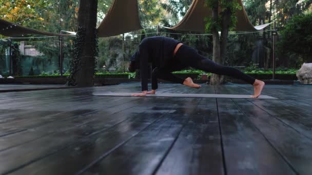 Adho Mukha Svanasana, Dog Pose. Mujer joven con apariencia oriental practicando yoga sola en cubierta de madera en isla tropical al atardecer. cámara lenta, 4k — Vídeos de Stock