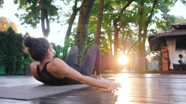 Κορίτσι κάνει Setu Bandha Sarvangasana, γέφυρα θέτουν. Νεαρή γυναίκα με ανατολίτικα εμφάνιση γιόγκα Kandharasana μόνο σε ξύλινο κατάστρωμα στο τροπικό νησί. 4k — Αρχείο Βίντεο