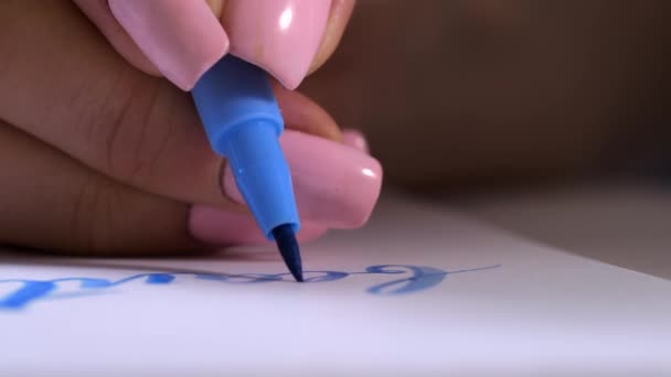 Крупный план руки каллиграфа пишет слово "красота" на белой бумаге. Написанные декоративные буквы. Каллиграфия, графический дизайн, письмо, почерк, концепция создания. 4k — стоковое видео