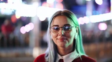 Hippi kız mavi boyalı saçlı ve çilli olarak altın pullu. Burun piercing, şeffaf gözlük, kulakları tüneller kadınla, sıradışı saç modeli eğlence gece parkta duruyor.