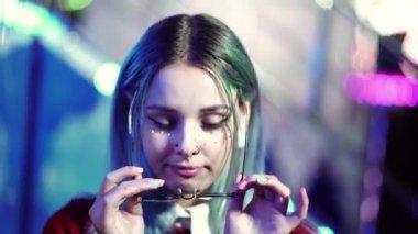 Hippi kız mavi boyalı saçlı ve çilli olarak altın pullu şeffaf gözlük koyar ve güzel yüzünü oluşturur. Burun piercing,, kulakları tünelleri, sıradışı saç modeli olan kadın