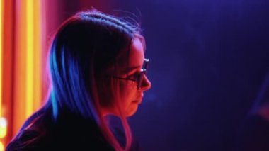 Bin yıllık gizemli güzel kızla gece parlak neon duvarının yakınında alışılmadık boyalı saç modeli. Saç, altın pullu çiller olarak mavi, piercing burun. Gizemli hipster genç gözlük.