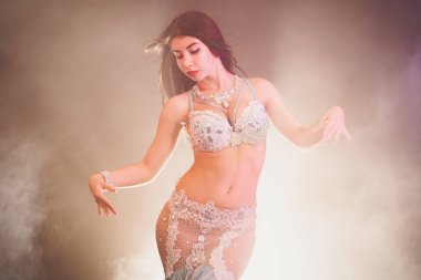 aydınlık duman arka plan üzerinde dans çok güzel seksi geleneksel Oryantal Dansöz kızı. Beyaz egzotik kostüm kadında cinsel onu yarı çıplak vücut hareketleri.