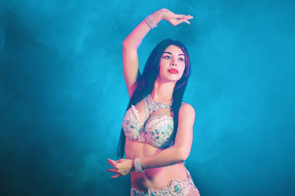 Kvinna i exotiska kostym flyttar sexuellt halvnakna kropp. Sexig traditionella orientaliska magdansös flicka dansa på blå neon vägg. Muslimer, frestelsen koncept. Spektakulär show — Stockfoto