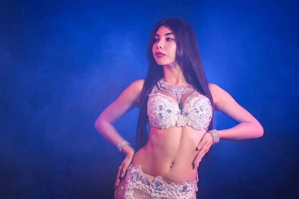 Kvinna i exotiska kostym flyttar sexuellt halvnakna kropp. Sexig traditionella orientaliska magdansös flicka dansa på blå neon vägg. Muslimer, frestelsen koncept. Spektakulär show — Stockfoto