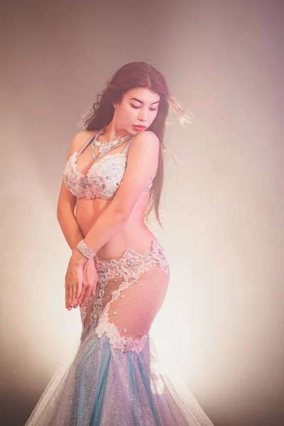 Adorabil sexy tradițional oriental fata dansatoare burtă dans pe fundal fum luminos. Femeia în costum exotic alb își mișcă sexual corpul semi-nud . — Fotografie, imagine de stoc