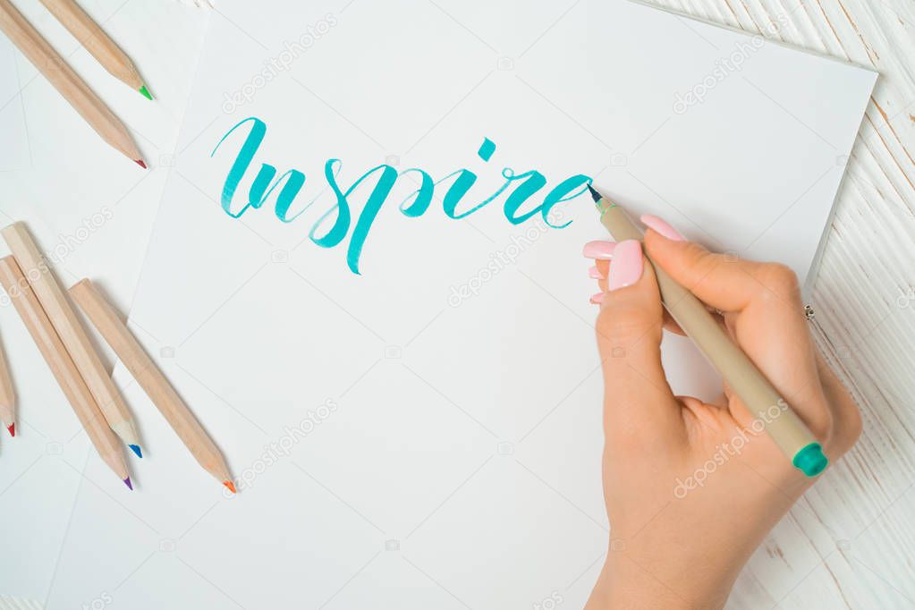 Calligrapher student practices in writing word inspire with green marker on canvas. Creative artist freelancer working on project at home studio. Lettering, handwriting concept.