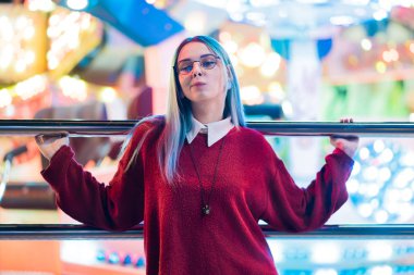 Hippi kız mavi boyalı saç ve payetler çiller olarak. Kırmızı giyim ve burun piercing, şeffaf gözlük, kulakları kadında tüneller, eğlence parkı içinde sıradışı saç modeli