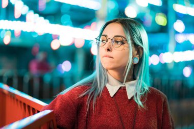 Hippi kız mavi boyalı saç ve payetler çiller olarak. Kırmızı giyim ve burun piercing, şeffaf gözlük, kulakları kadında tüneller, eğlence parkı içinde sıradışı saç modeli