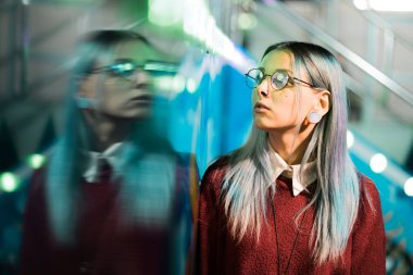 Hippi kız mavi boyalı saç ve payetler çiller olarak. Kırmızı giyim ve burun piercing, şeffaf gözlük, kulakları kadında tüneller, eğlence parkı içinde sıradışı saç modeli