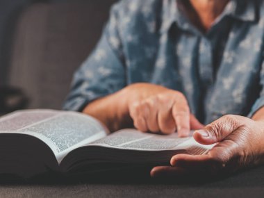 Yaşlı kadın evde kalın bir kitap okuma. İncil ile büyükanne. Konsantre yaşlı emekli kırışıklıkları elleri ile kağıt sayfa kitaplığı'nda parmak dikkatle takip