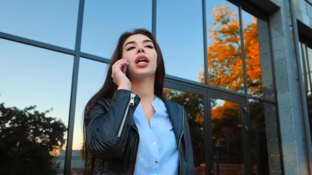 Donna d'affari con smartphone da vicino vicino vicino edificio per uffici. La ragazza parla con il cellulare. Bella giovane donna caucasica che parla con dispositivo mobile . — Video Stock