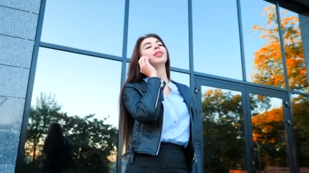 Donna d'affari con smartphone da vicino vicino vicino edificio per uffici. La ragazza parla con il cellulare. Bella giovane donna caucasica che parla con dispositivo mobile. 4k — Video Stock