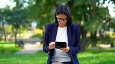 Tablet bilgisayarda yeşil park arka plan ile başarılı bir iş kadını. Formal giyim ve internet'te sörf veya elektronik cihaz üzerinde gözlük güzel kız