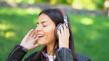 Mutlu karışık yarış genç kadın kulaklıklar müzik dinlemek. Dans ritim ve melodi Park boyunca şarkı İspanyol hippi kız