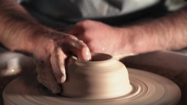 Toprak ve geleneksel seramik konsept oluşturma. Erkek potters eller güzel kil ürün - kase - profesyonel araçlar kullanarak oluşturma deneyimli. Tonda sinematik, zanaat fabrika otantik