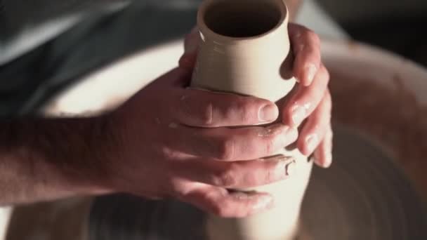 Традиционное керамическое производство, человек учитель показывает основы керамики в художественной студии. Художник управляет руками, которые аккуратно создают правильную форму ручной работы из глины. 4k — стоковое видео