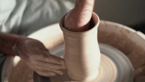Schuss halbfertiger Keramikvase, die sich auf einem Rad dreht. Nahaufnahme männlicher Hände, die an Töpfern arbeiten. Kleinunternehmer Handwerker, der in der Werkstatt arbeitet. 4k — Stockvideo