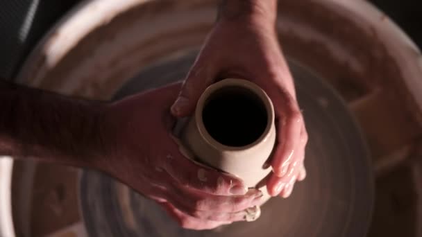 Vedere generală a omului care face oală pe roata ceramicii. Potter modelează produsul din lut - vază sau cană - cu instrumente profesionale, vedere de sus. Proprietar de afaceri mici care lucrează în atelier — Videoclip de stoc