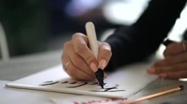 Hattat eller yazar ifade beyaz kağıt üzerinde. Süs süslü harfler inscribing. Hat sanatı hocası, grafik tasarım, harfler, el yazısı, yaratma kavramı. Ağır çekim.