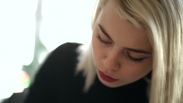 Retrato de cerca de una joven sentada en una biblioteca u oficina y trabajando con papeles o libros. Mujer rubia con maquillaje perfecto y peinado corto. Educación, concepto empresarial . — Vídeos de Stock