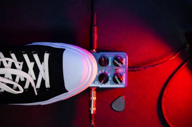 Gitar çalar ayak pedal basarak kapatın. Müzisyen müzik etkisi döngü makine kullanır. Adam son moda spor ayakkabıları, konser sırasında aşamada oynarken ayağı. Makro görünümü