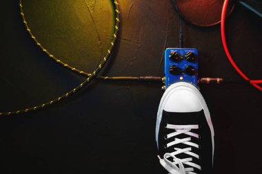 Gitar çalar ayak pedal basarak kapatın. Müzisyen müzik etkisi döngü makine kullanır. Adam son moda spor ayakkabıları, konser sırasında aşamada oynarken ayağı. Makro görünümü.