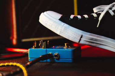 Gitar çalar ayak pedal basarak kapatın. Müzisyen müzik etkisi döngü makine kullanır. Adam son moda spor ayakkabıları, konser sırasında aşamada oynarken ayağı. Makro görünümü