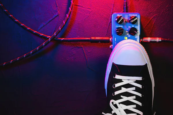 Guitar pedals and footswitch inside recording room. Close up of guitar pedals and musicians foot tapping on it for different sounds. Macro view. Copy space.