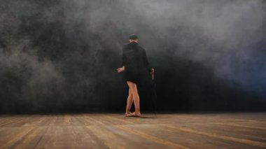 Balerin sihirli ışık ve duman, yavaş hareket ile sahnede dans seksi elbise üzerinde siyah uzun ceketli. Bale ayakkabıları pointe şemsiye ile genç çekici dansçı