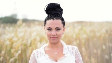 Afrika olan güzel kadın portresi saç modeli ayakta sazlık alanda örgü. Sonbahar sezonu. Çingene kızı kameraya bakarak ve gülümseyen boho-bohem dantel beyaz elbiseli