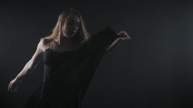 Profesyonel Balerin Bale projektör duman büyük sahnede. Projektörler arka plan üzerinde siyah dar elbise giymiş uzun saçlı güzel beyaz genç kız. ağır çekim.