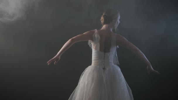 SLOW MOTION. unrecognizable beautiful ballerina performing on dark smoke stage. Blonde woman in white ballet dress tutu dancing with hands — Stock Video