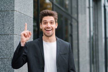 Eureka jest gösterilen gülümseyen mutlu öğrenci adam. Arka bina ofis parmak işaret fikir an sahip genç düşünme durulması işadamı portresi