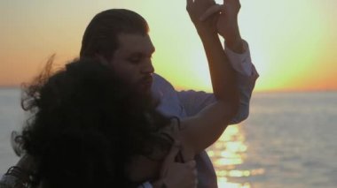 Genç çekici çift latin bachata deniz ya da okyanus yakın dans portresi. Güneş ışığı arka plan. Yaz saati, romantik görüntüleri. Ağır çekim