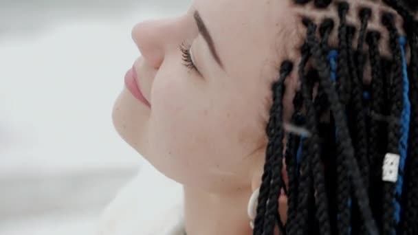 Jeune femme avec des tresses bleues kanekalon africaines marchant sur la plage de la mer d'hiver. Coiffure afro, cheveux teints. Fille en fourrure blanche s'amuser pendant la neige. Blizzard . — Video