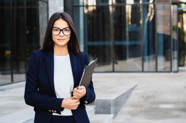 Gözlük takan ve kamera, profesyonel kadın Yöneticisi Kurumsal takım elbise isteyen genç başarılı işkadını portresi. Öğrenci kız, ücret çalışan, hafta içi kavramı