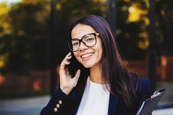 Businesswoman have conversation using mobile phone. Business girl in glasses and formal suit joyfully talks with colleague. Office employee, wage worker, weekdays concept