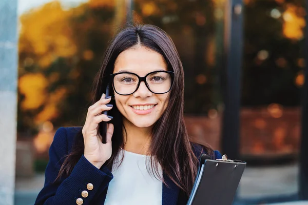 Businesswoman have conversation using mobile phone. Business girl in glasses and formal suit joyfully talks with colleague. Office employee, wage worker, weekdays concept