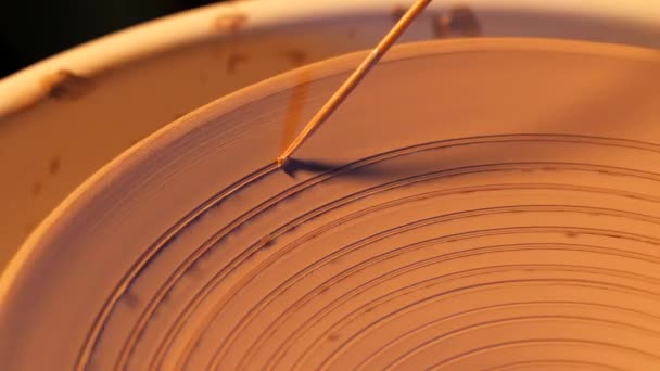 Vy över mannen att göra plattan på keramik hjul. Potter skapar ett spiralmönster på det med professionella verktyg. Småföretagare som arbetar i verkstad. Makro bilder. 4k — Stockvideo