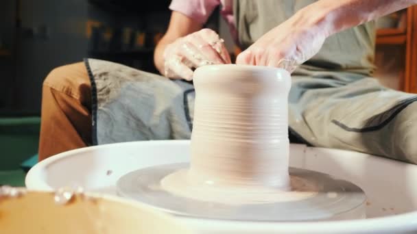 L'homme travaille ses mains avec de l'argile. Processus de création de produit à partir d'argile sur la roue des potiers. Vue latérale de l'artisan faisant pot ou cruche. Propriétaire de petite entreprise en atelier — Video