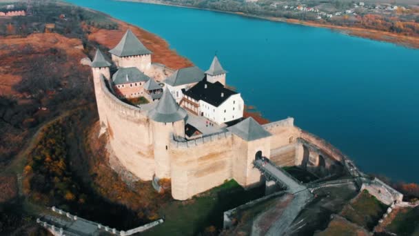 Légi panoráma nyílik a régi Hotin vára a folyó közelében. Chocimi erőd - középkori vár, a sárga-őszi hegyekben. Ukrajna, Kelet-Európában. Építészet, a középkorban a mi korunkban. — Stock videók