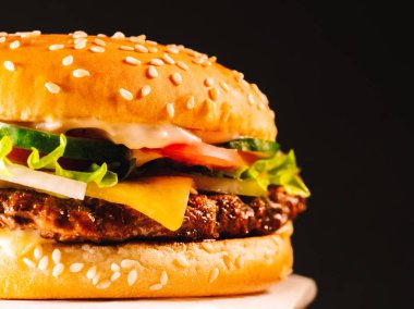 Sulu biftek burger göğsü, soğan, sebze, eritilmiş peynir, marul, sos ve susam tepesinde. İzole hamburger koyu duman arka plan üzerinde yakından görmek döner